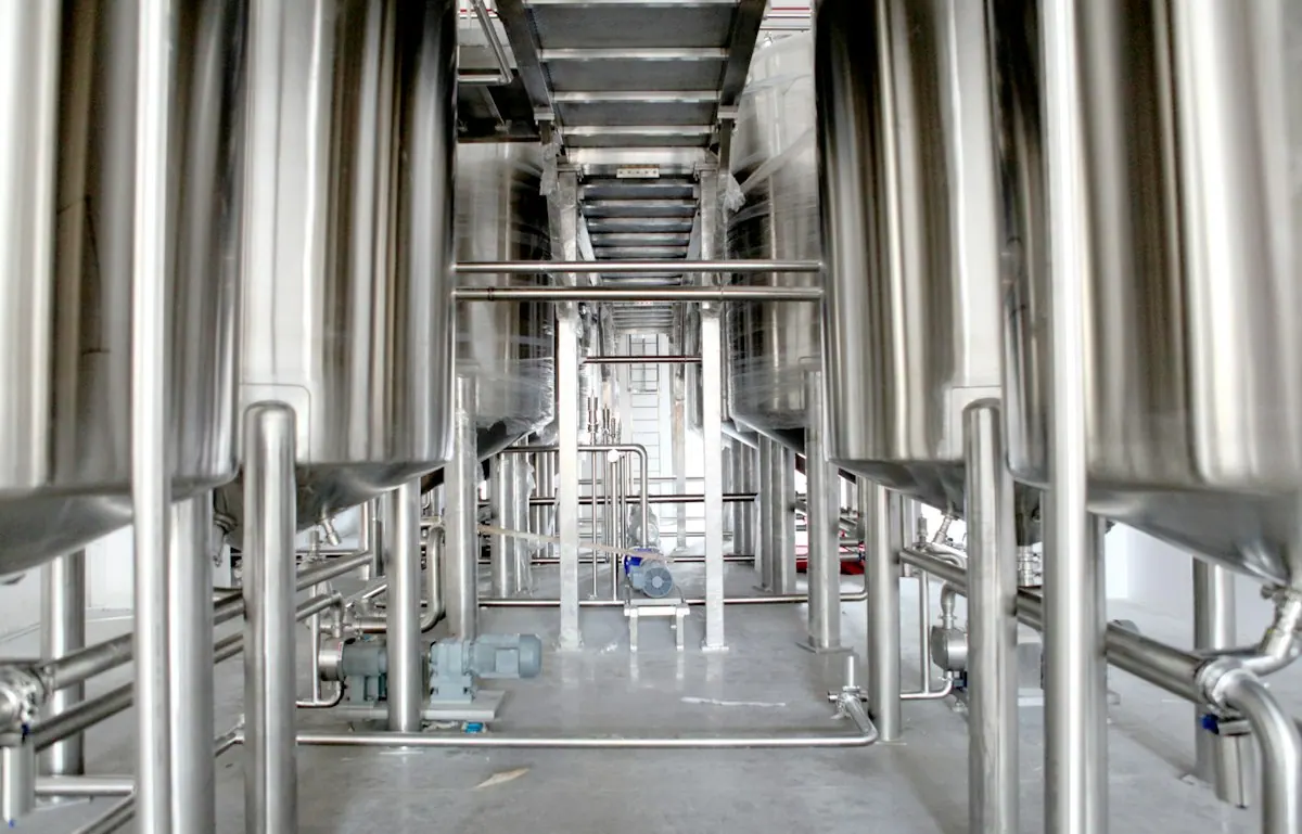 Stainless-steel tanks and pipework along a factory aisle